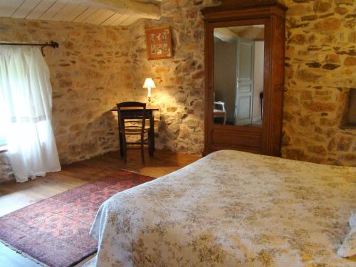 a bedroom with a bed and a table and a mirror at Nabat le Haut, chambre et table d'hotes in Courniou