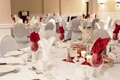 a table with white chairs and red napkins and glasses at L'Escale Hôtel Suites in Val-dʼOr