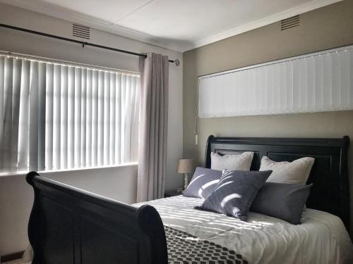 um quarto com uma cama com uma cabeceira preta e uma janela em Take a Break Self Catering Accommodation em Knysna