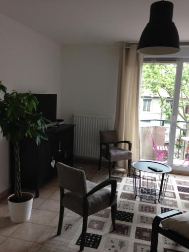 ein Wohnzimmer mit einem Tisch, Stühlen und einem Fenster in der Unterkunft Chez Marie in Lyon