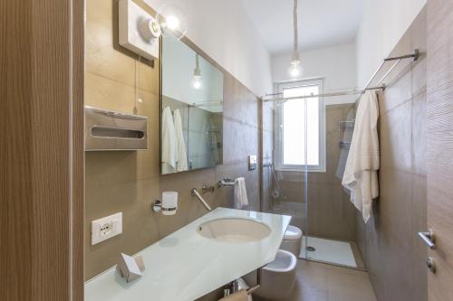 a bathroom with a sink and a toilet and a mirror at Hotel Tannure in San Vito lo Capo