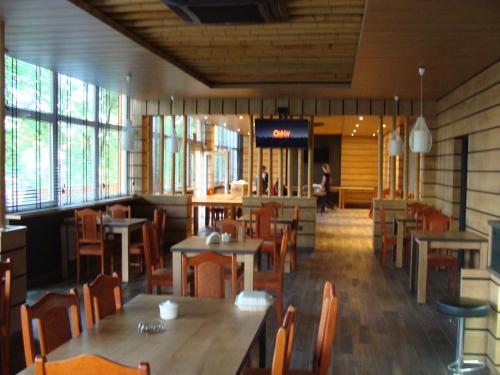 イワヴァにあるLeśna Przystań- akceptujemy bony turystyczneの木製のテーブルと椅子、人々を背景に設置したレストラン