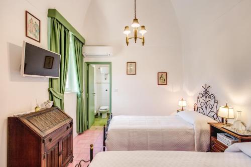 a hotel room with two beds and a flat screen tv at B&B "i Magi" in Anacapri