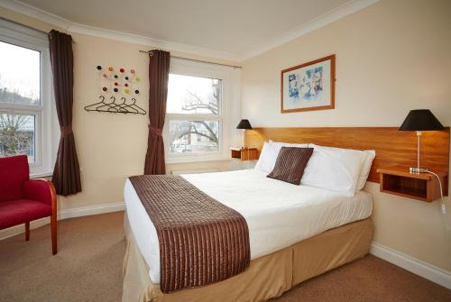 a bedroom with a large bed and a red chair at The Terrace Lodge Hotel in Yeovil