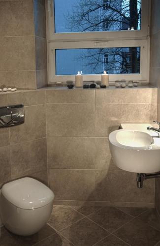 a bathroom with a sink and a toilet and a window at Apart Rooms Marszalkowska by WarsawResidence Group in Warsaw