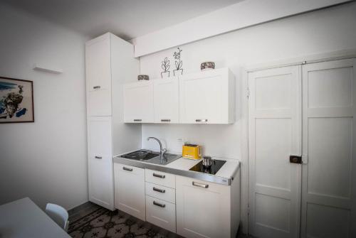 a small kitchen with white cabinets and a sink at Luxury Apartments Manarola by Arbaspàa in Manarola