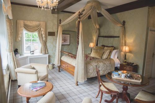 a bedroom with a canopy bed and a table at Mere Court Hotel in Knutsford