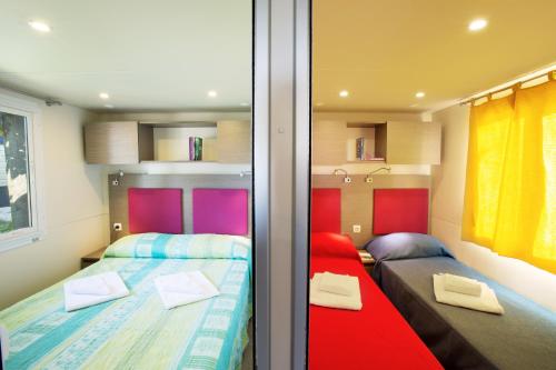 a small bedroom with two beds and a window at La Rocca Camping Village in Bardolino