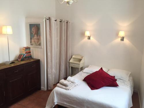 a bedroom with a bed with white sheets and red pillows at Studios Floreal in Nice