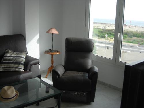 a living room with a chair and a glass table at Apartamento Dos Faros in Conil de la Frontera