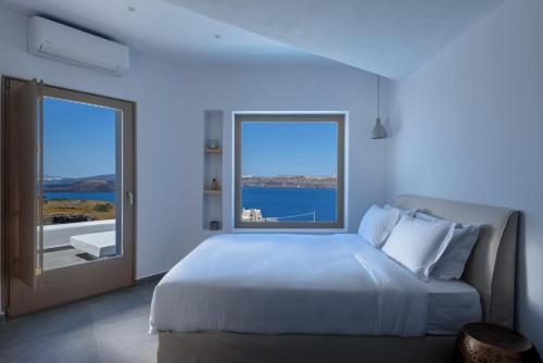 sypialnia z dużym łóżkiem i dużym oknem w obiekcie Earino Suites and Villa w Akrotiri