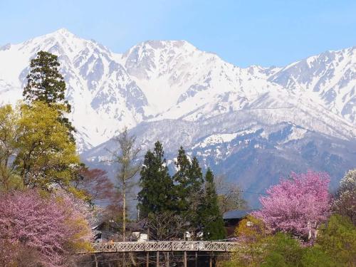 a mountain range with trees and snow covered mountains at 一組限定の貸切空間 Guest House Engiya in Matsumoto
