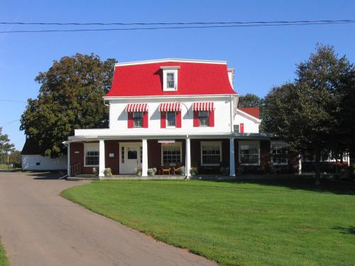 a large white house with a red roof at Shaw's Hotel & Cottages in Brackley Beach