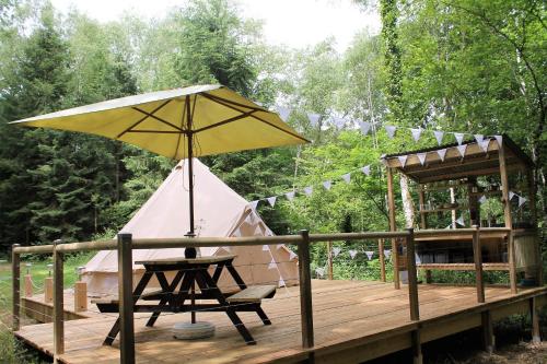 Tienda de campaña con silla y sombrilla en la cubierta en Camping Moulin De La Geneste en Condat-sur-Ganaveix