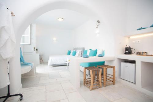 a white room with a bed and a table with stools at Mykonos Moussa in Agios Ioannis Mykonos