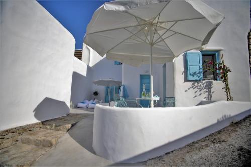 a white building with a large white umbrella at Mykonos Moussa in Agios Ioannis Mykonos