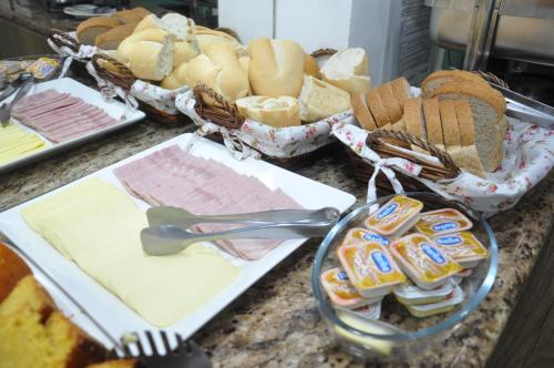 a counter top with bread and sandwiches and utensils at Bonjour Hotel in Macaé