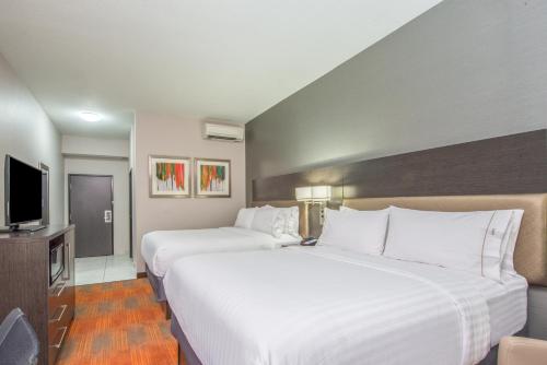 a hotel room with two beds and a flat screen tv at Holiday Inn Express Shawnee by IHG in Shawnee