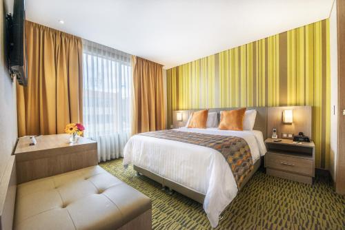 a hotel room with a bed and a large window at Hotel Plaza Suites in Bogotá