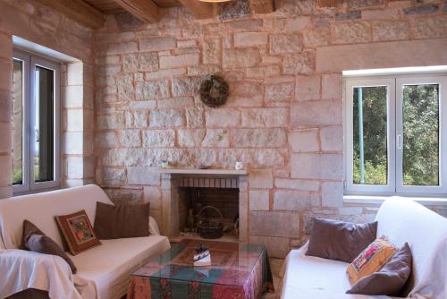 a living room with a stone wall with a fireplace at Pantanassa Villas in Agia Marina Nea Kydonias