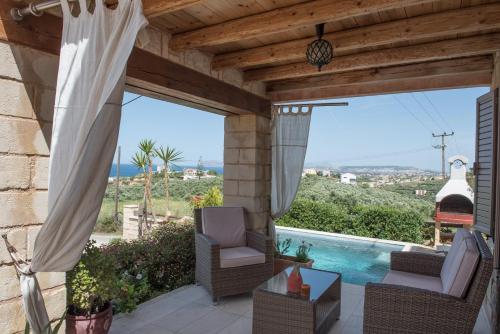a patio with two chairs and a swimming pool at Pantanassa Villas in Agia Marina Nea Kydonias
