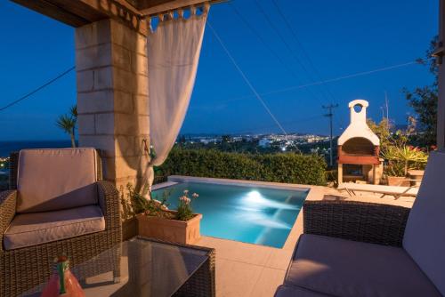 a backyard with a swimming pool and two chairs at Pantanassa Villas in Agia Marina Nea Kydonias
