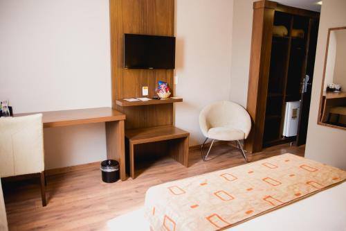 a room with a bed and a desk and a chair at Class Hotel Varginha in Varginha