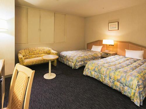 a hotel room with two beds and a couch at Tsubamesanjo Washington Hotel in Sanjo