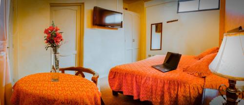 a bedroom with a laptop on a bed and a table at Hotel Monserrat in Cochabamba