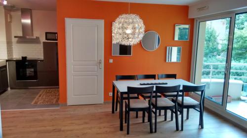 a dining room with orange walls and a table and chairs at lille grand boulevard in Marcq-en-Baroeul