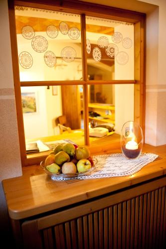 a bowl of fruit on a table with a glass of wine at Agritur Renetta in Tassullo