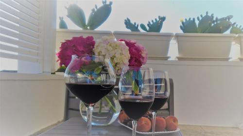 two glasses of wine on a table with flowers at Innsud in Nardò