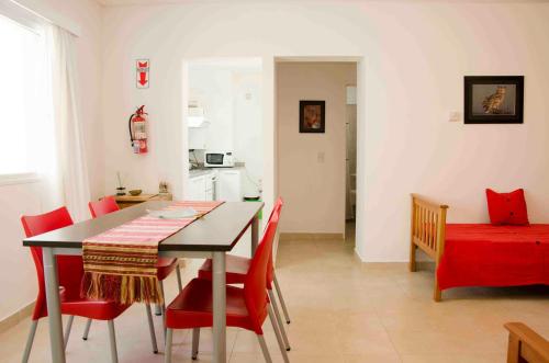 a kitchen and dining room with a table and red chairs at Las Anémonas Centro in Puerto Madryn