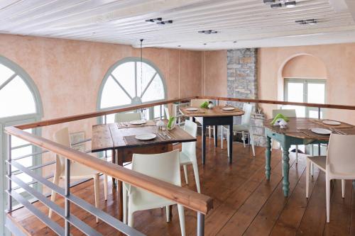 un restaurante con mesas y sillas de madera y ventanas en Guesthouse Lila, en Ermoupoli