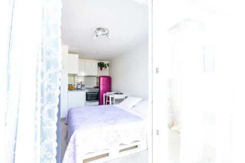 a white bedroom with a bed and a kitchen at Apartments Laura in Korčula