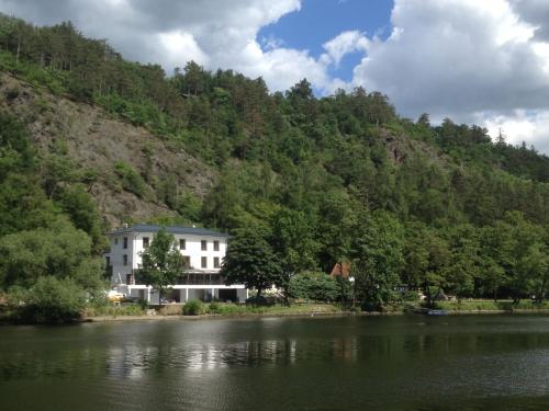 a white house on the side of a lake at Hotel Mandát in Hradištko