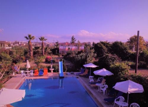a swimming pool with umbrellas and tables and chairs at Violetta Hotel in Amoudara Herakliou