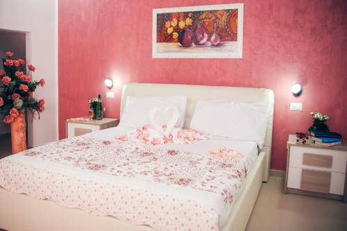 a bedroom with a white bed with a pink wall at Il Sorriso B&B in Ugento