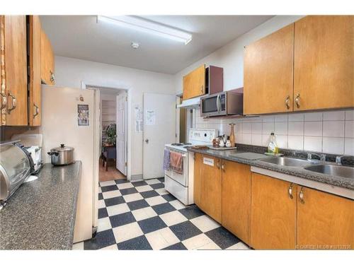 a kitchen with wooden cabinets and a checkered floor at Kelowna Okanagan Lake Hostel in Kelowna