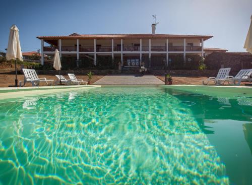 a swimming pool in front of a house at Varandas da Capela in Tuizelo