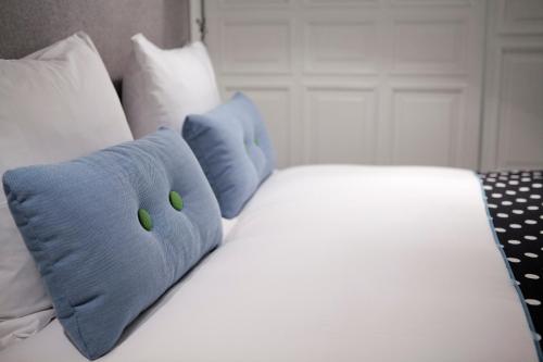 a white bed with blue pillows on top of it at Hotel Manna in Nijmegen