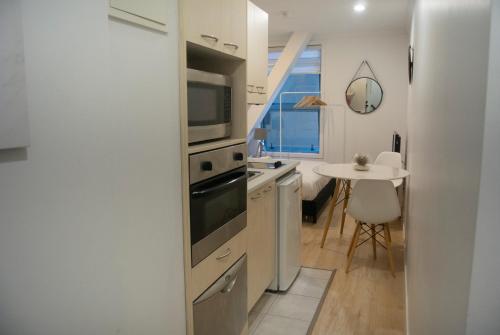 a kitchen with a sink and a microwave and a table at Snug Studio in the heart of the city in Auckland