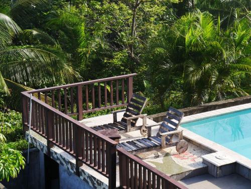 two chairs sitting on a deck next to a swimming pool at Punta Duarte Garden Inn in Los Duarte