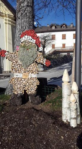 a statue of a person standing next to a tree at Haus Green & Spa Angelika Trentino in Lavarone