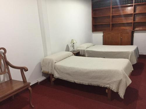 a room with two beds and a chair and a table at Posada Casa de Borgoña in Salta