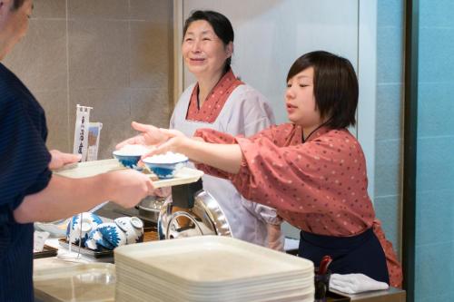 a woman standing in front of a mirror holding a plate at Yuzawa Grand Hotel in Yuzawa