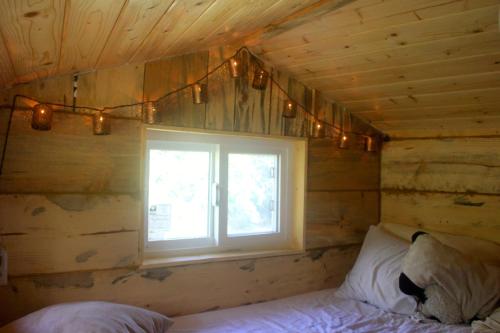 a bedroom with a window in a wooden wall at Hawk's Rest in Oakhurst