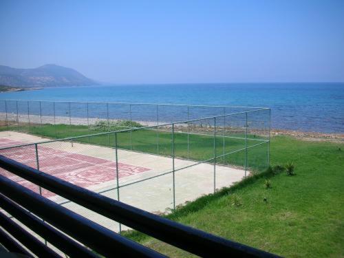 a tennis court in front of the ocean at Souli Beach Hotel in Polis Chrysochous