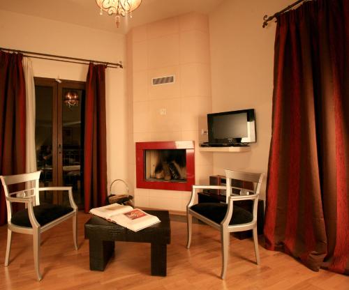a living room with two chairs and a tv at Epavlis Meteora Suites Hotel in Kalabaka