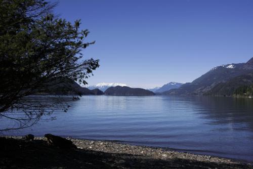a view of a lake with mountains in the background at The Rockwell-Harrison Guest Lodge in Harrison Hot Springs